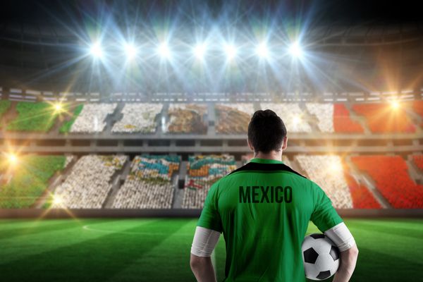 بازیکن فوتبال مکزیک در حالی که توپ را در مقابل استادیوم پر از هواداران فوتبال مکزیکی نگه داشته است