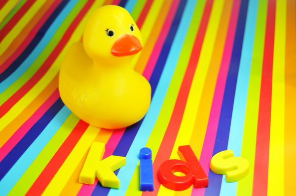 اردک لاستیکی در پس زمینه بچه ها رنگارنگ