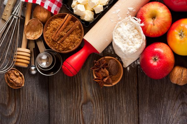 مواد لازم برای پخت پای سیب سیب قرمز تازه کره آرد شکر قهوه ای آجیل و ادویه جات ترشی جات در زمینه چوبی روستایی