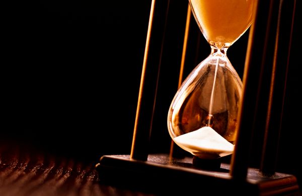 ساعت شنی تازه تبدیل شده با ماسه روان که زمان گذر تا یک مهلت یا انقضای یک دوره زمانی ثابت را اندازه‌گیری می‌کند از نزدیک در پس‌زمینه تیره