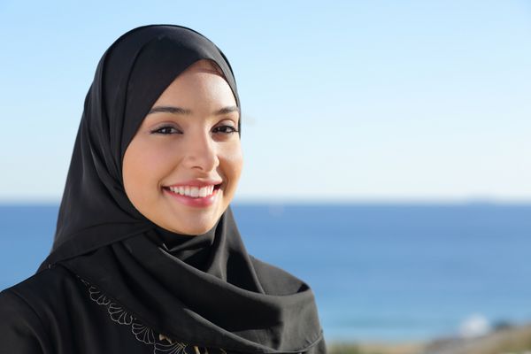 زن زیبای عربستان سعودی در حال ژست گرفتن در ساحل با دریا در پس زمینه