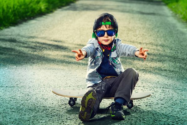 پسر 7 ساله باحال با اسکیت بردش در خیابان دوران کودکی تابستان