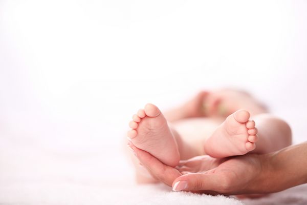 پاهای نوزاد تازه متولد شده روی دست های زن