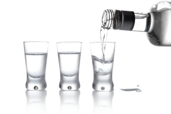 نمای نزدیک از بطری و لیوان های ریخته شده در لیوان ایزوله شده روی سفید