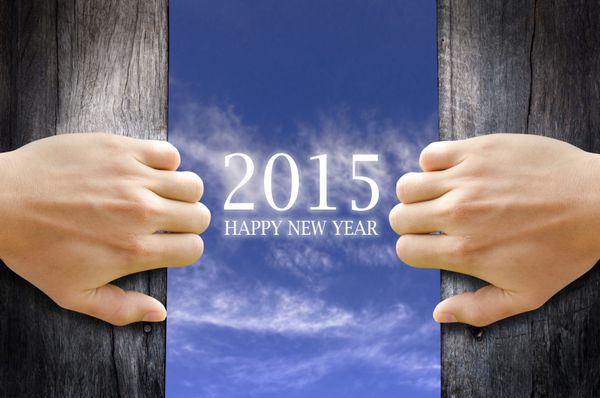 متن تبریک سال نو 2015 در آسمان پشت 2 دستی که در چوبی را باز می کند