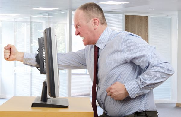تاجر در دفتر در خشم با صفحه نمایش کامپیوتر