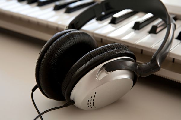 طبیعت بی جان از دو دستگاه موسیقی الکترونیکی و صدا که روی یک میز سفید در یک استودیوی ضبط صدا کنار هم قرار گرفته اند نمای جزئیات یک جفت هدفون و یک صفحه کلید فناوری