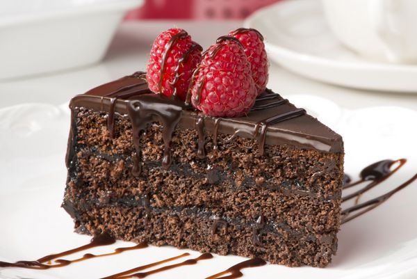 تکه ای از کیک لایه شکلاتی با انواع توت ها و سس شکلات