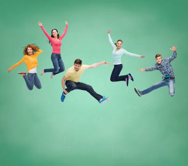 شادی آزادی دوستی آموزش و مفهوم مردم - گروهی از نوجوانان خندان که در هوا بر روی پس زمینه تخته سبز می پرند