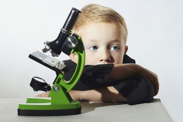پسر کوچولو نمیخواهد درس بخواند کودک غمگین کودکان دبستانی با میکروسکوپ پسر باهوش آموزش