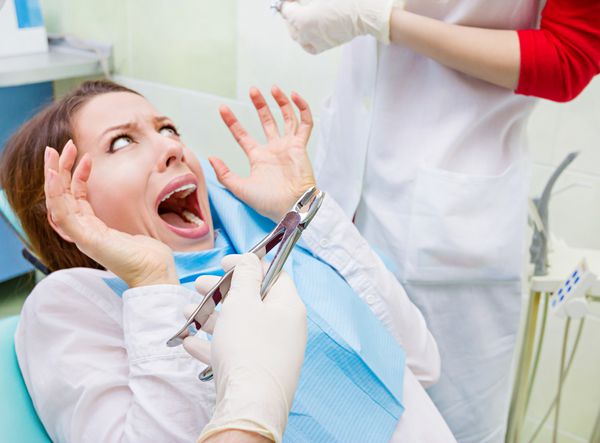 پرتره نزدیک دختر جوان وحشت زده زن ترسیده در ملاقات با دندانپزشک نشسته روی صندلی جیغ زدن دهان باز شده نمی خواهد عمل دندانپزشکی کشیدن دندان دریل کردن دندان پس زمینه مطب کلینیک ایزوله
