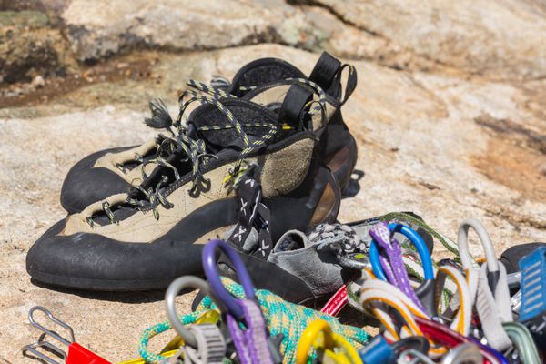نمای نزدیک از طناب و کارابین کفش کوهنوردی حنایی و مشکی روی گرانیت قبل از صعود