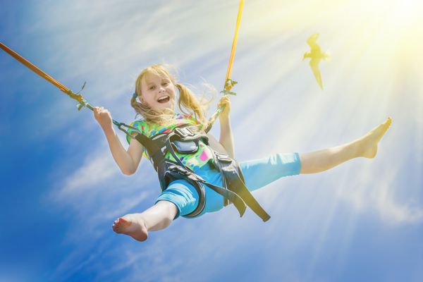 دختر کوچک شادی که بر فراز آسمان آبی پرواز می کند