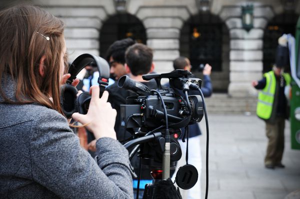 ناتینگهام انگلستان - 28 آوریل 2011 خبرنگار زن جوان تجهیزات صوتی و تصویری را برای مصاحبه خیابانی آماده می کند