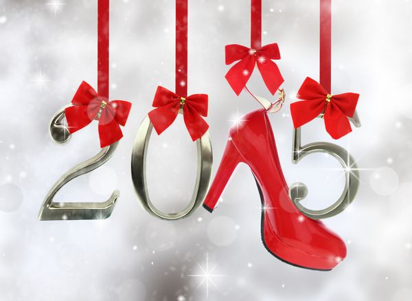کفش پاشنه بلند و شماره 2015 آویزان شده روی روبان های قرمز در پس زمینه پر زرق و برق