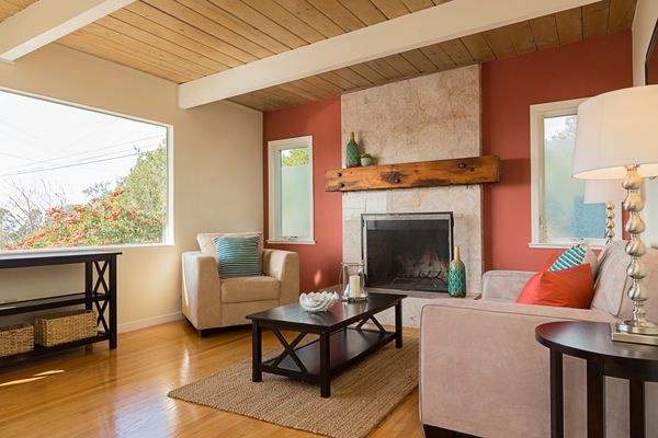 فضای داخلی اتاق نشیمن کلاسیک قرمز و سفید با نمای پنجره و کف چوبی بالش‌های آتشین و قرمز آبی روی مبل کاناپه با سیزال ظریف رنگی طبیعی دست‌بافت فرش