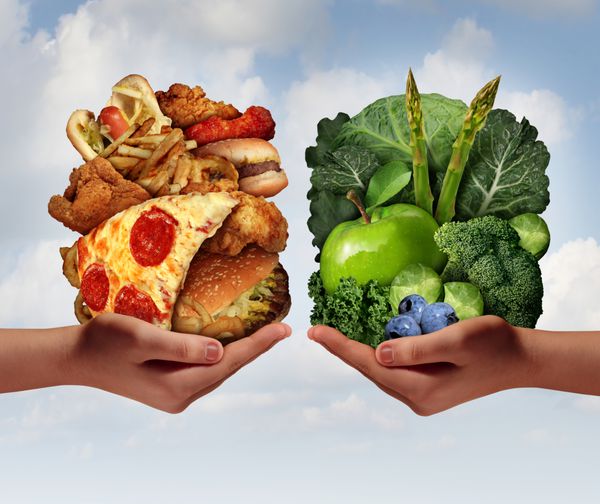مفهوم انتخاب تغذیه و تصمیم گیری رژیم غذایی و دوراهی خوردن بین میوه و سبزیجات سالم سالم و تازه یا فست فود غنی از کلسترول چرب با دو دست که گزینه های غذایی را در دست گرفته اند