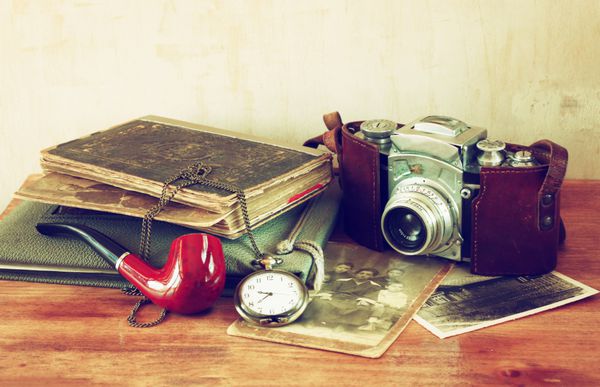 دوربین قدیمی عکس های عتیقه و ساعت جیبی قدیمی روی میز چوبی