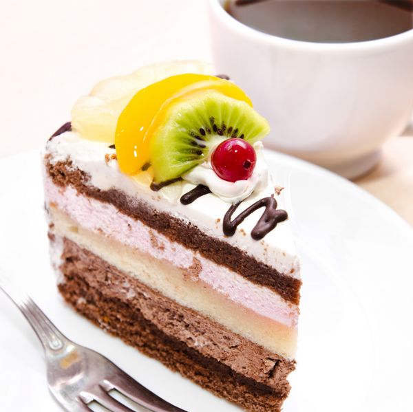 تکه کیک شکلاتی با میوه در بشقاب و فنجان چای
