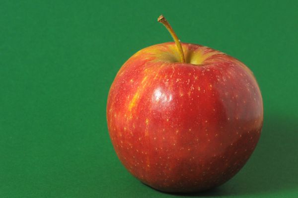 یک سیب قرمز آبدار روی پس زمینه رنگی