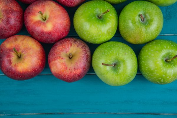 سیب های ارگانیک قرمز و سبز پاییزی تازه روی میز آبی چوبی رترو مزرعه کنید