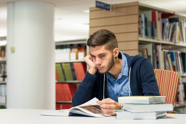 حوصله دانشجوی مرد در حال خواندن کتاب در کتابخانه درس خواندن برای امتحان انجام تحقیق برای پروژه دانشگاه دانش مفهوم قدرت است