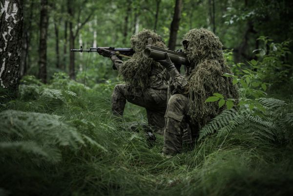 گروهی از سربازان نیروهای ویژه در جنگل با پرتابگر et هدف قرار می دهند سربازانی که لباس های گلی بر تن دارند بر روی طبیعت استتار می کنند
