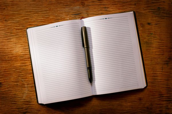 دفترچه یادداشت باز روی میز و خودکار برای برنامه ریزی تجاری