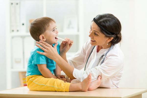دکتر در حال معاینه پسر کوچک جدا شده در زمینه سفید