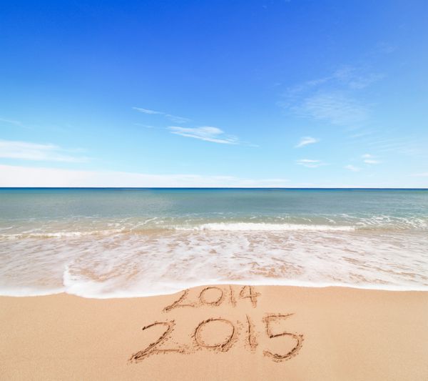 مفهوم سال جدید 2015 در راه است - کتیبه 2014 و 2015 بر روی شن و ماسه ساحل موج در حال پوشش ارقام 2014 است