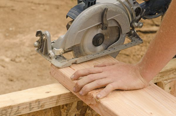 پیمانکار قاب بندی با استفاده از یک اره دایره ای دستی برای کوتاه کردن طول میخ های چوبی