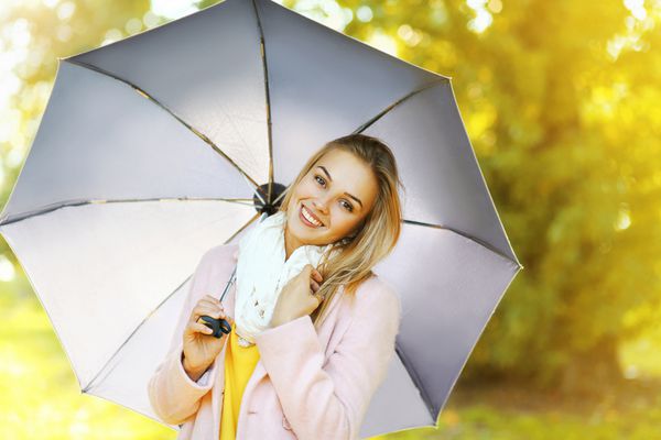 زن زیبا با چتر در روز پاییز