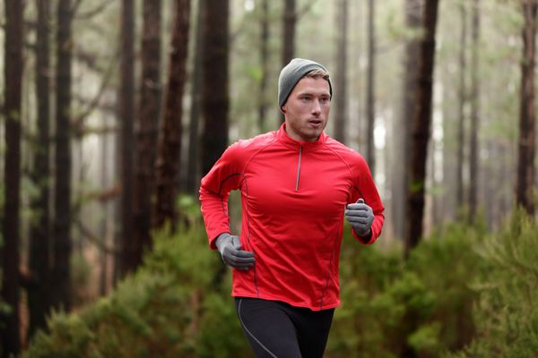 مرد دونده در جنگل جنگل آموزش و ورزش برای دویدن در مسیر ماراتن استقامت r مفهوم سبک زندگی سالم تناسب اندام با ورزشکار تریل دونده مرد