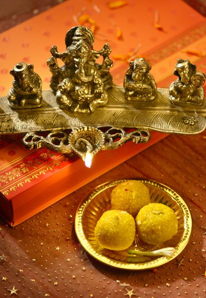 یک چراغ مجسمه گانشا متالیک با شیرینی هندی