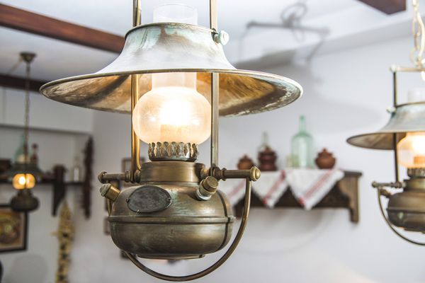 چراغ تزئینی فلزی قدیمی قدیمی با پتینه آویزان در سقف داخلی یک میخانه روسی لامپ برقی به سبک روستیک شبیه لامپ نفت سفید روستایی عتیقه