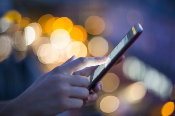 زن با استفاده از تلفن همراه خود پس زمینه نور شب افق شهر