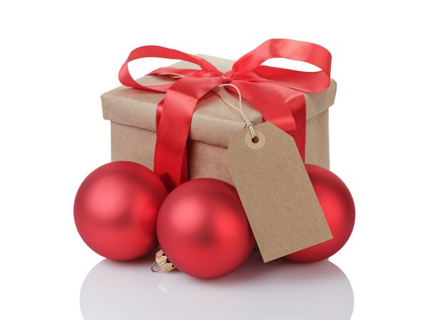 جعبه هدیه پیچیده شده با پاپیون قرمز توپ های کریسمس و برچسب جدا شده روی سفید