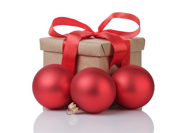 جعبه هدیه پیچیده شده با پاپیون قرمز و توپ های کریسمس جدا شده روی سفید