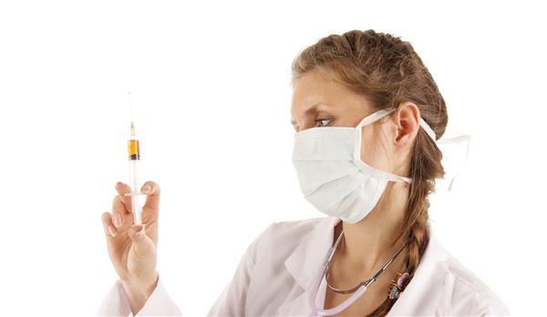 پرستار جوان زیبا که به سرنگ همراه دارو نگاه می کند