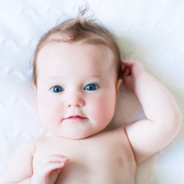 کودک چشم آبی زیبا روی یک پتوی بافتنی سفید