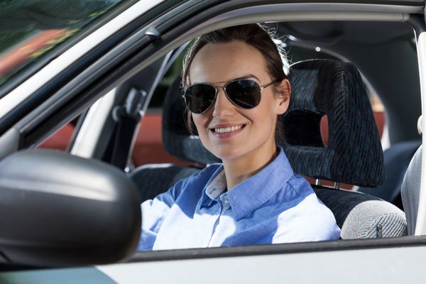 زن جوانی که روی صندلی راننده نشسته و لبخند می زند
