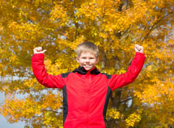 پسر شاد در پارک پاییز سقوط سرگرمی کودک در فضای باز درختان و برگ های زرد رنگ مفهوم آزادی