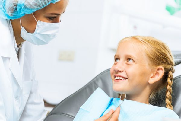 دختر ناز کوچکی که روی صندلی دندانپزشکی نشسته است