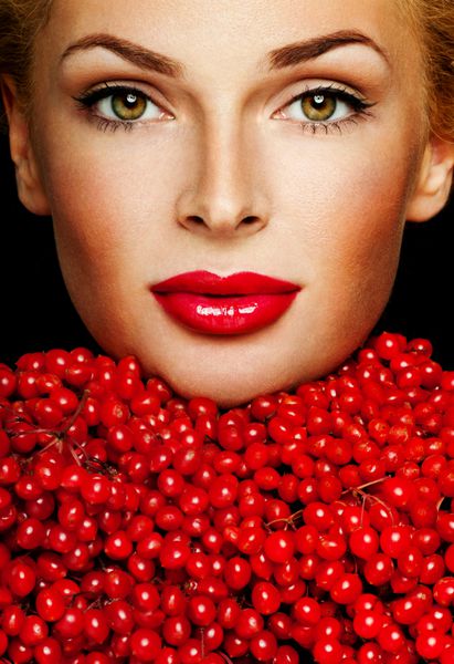 یک زن زیبا که توسط توت های قرمز احاطه شده است