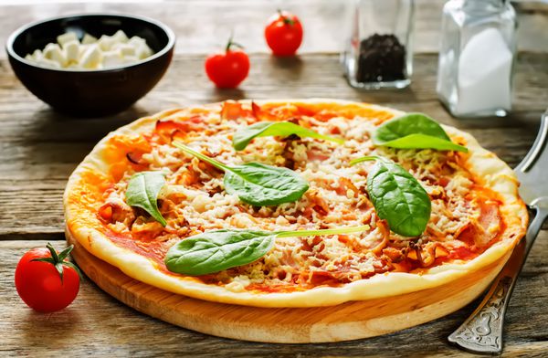 پیتزا با بیکن موزارلا و اسفناج در زمینه چوبی تیره رنگ آمیزی تمرکز انتخابی روی اسفناج