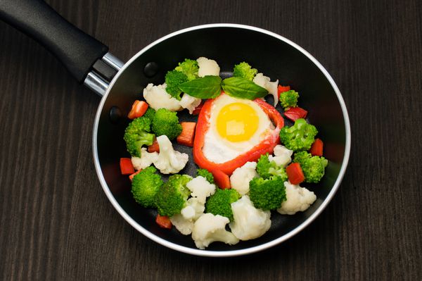 تخم مرغ های همزده با سبزیجات در ماهیتابه روی سیاه
