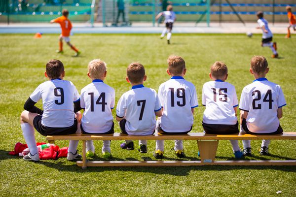 مسابقه فوتبال فوتبال برای کودکان بچه هایی که روی نیمکت منتظرند