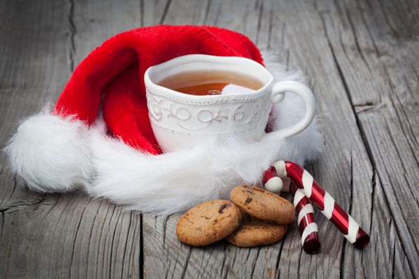 فنجان چای و کوکی های چیپسی شکلاتی در پس زمینه چوبی قدیمی زمان کریسمس