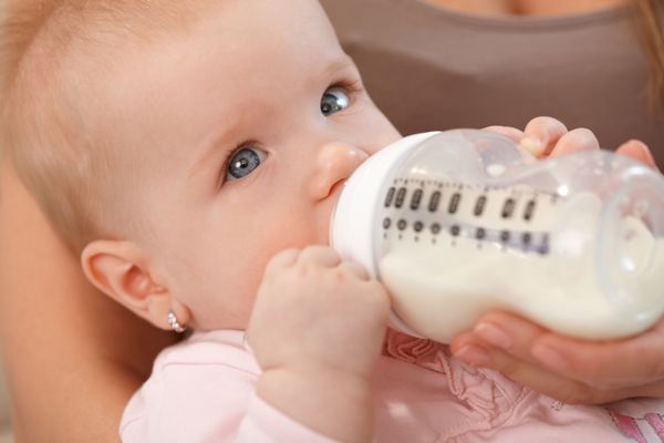 نمای نزدیک از دختر بچه زیبا در حال نوشیدن شیر از شیشه شیر