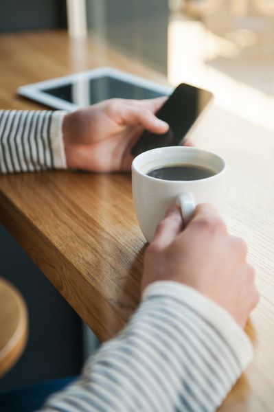 هیچ دقیقه ای بدون فناوری نیست نمای نزدیک مردی که تبلت دیجیتالی در دست دارد در حالی که از قهوه در کافه لذت می برد